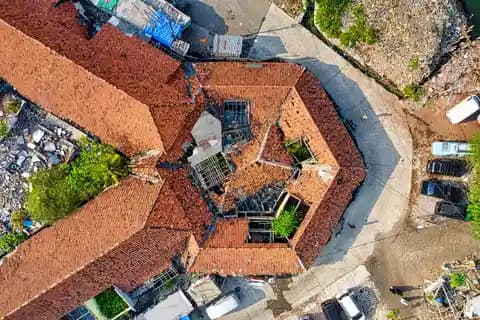 Drone terbang di atas atap bangunan yang rusak setelah badai untuk survei asuransi