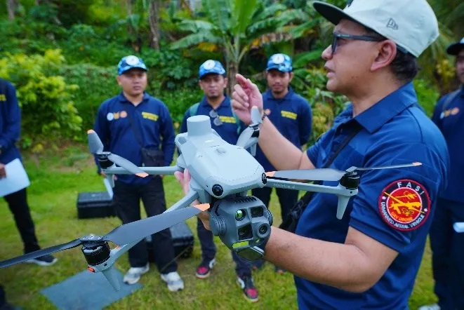 Instruktur memberikan pengarahan praktik terbang drone kepada peserta bimbingan teknis di lapangan