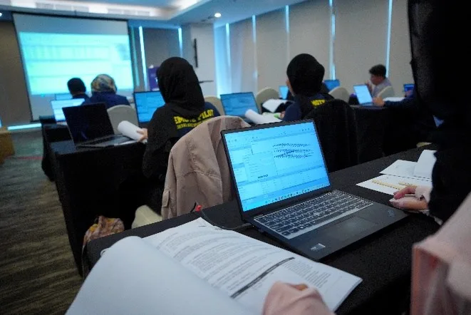 Peserta pelatihan mengerjakan ujian teori drone menggunakan laptop dan modul cetak