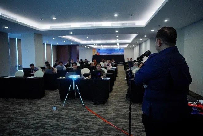 Instruktur menyampaikan materi regulasi penerbangan drone menggunakan mikrofon di depan peserta pelatihan